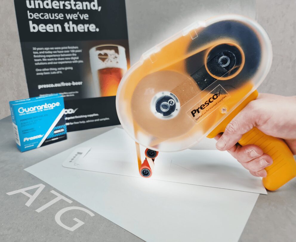 Hand using Presco tape dispenser on paper.