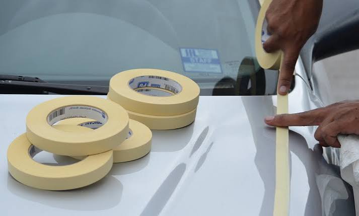 Applying masking tape on a car.