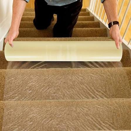 Man applying protective film on carpeted stairs.