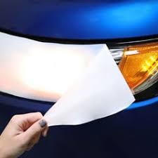 Hand holding paper near car headlight.