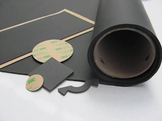 Roll of black rubber sheeting on a white surface, with a few other objects scattered around it