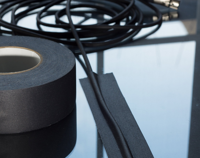 Roll of black tape sitting on top of a glass table, with a black wire