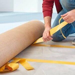 Workers installing flooring with cloth tape.